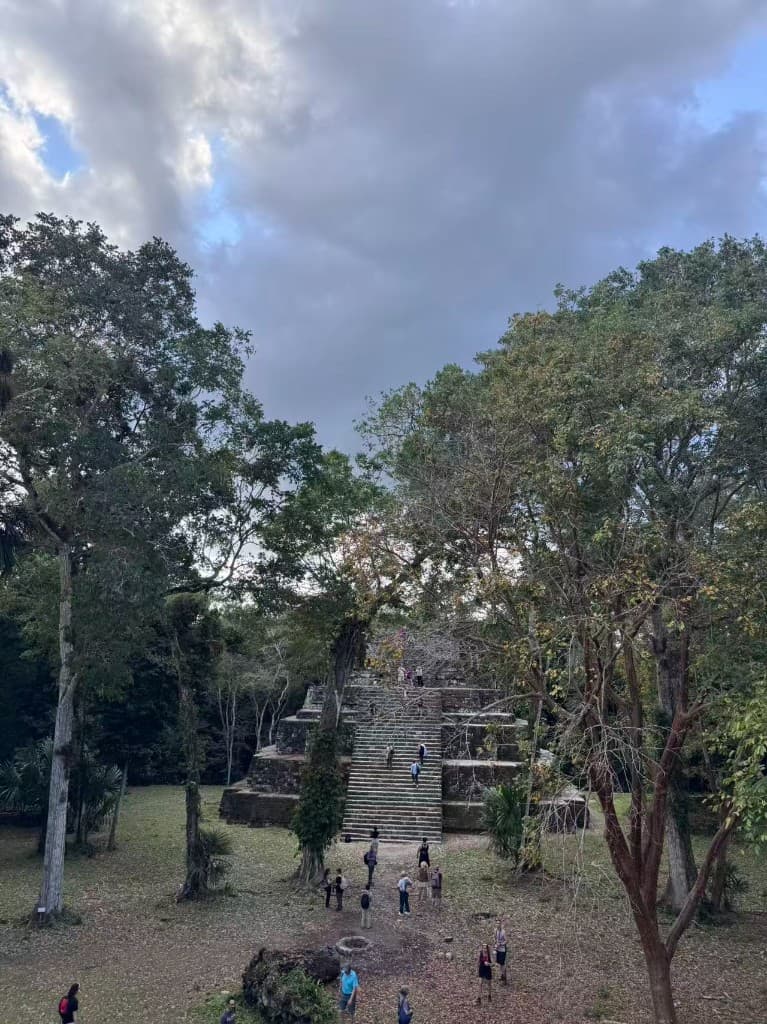 Mayan stepped pyramid at Yaxhá surrounded by jungle with visitors on the stairs, Guatemala